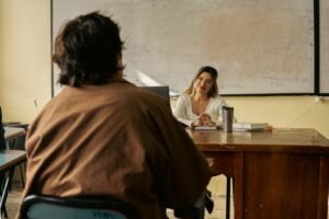 Professora conversando com aluno em sala de aula, tema de dupla aposentadoria de professores